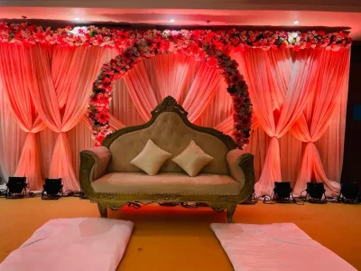 Elegant wedding stage decoration in a premium banquet hall with floral backdrop and luxury seating
